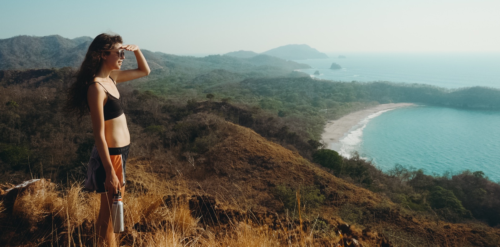 Dreamsea Costa Rica Surf Camp | backpacking, travel, hostel, surf, and yoga camp | Media Files | Lifestyle Image of Surf and Yoga Camp Resort | Young girl on top of a mountain looking out over costa rica's beach and ocean