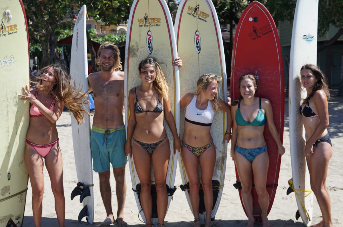 Dreamsea Costa Rica Surf Camp | backpacking, travel, hostel, surf, and yoga camp | Media Files | Lifestyle Image of Surf and Yoga Camp Resort | Group of girls and guys holding surf boards in their hands behind them while posing for a photo on a beach in Tamarindo, Costa Rica at Dreamsea Surf Camp