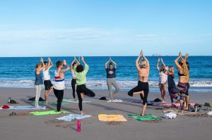 Dreamsea Costa Rica Surf Camp | backpacking, travel, hostel, surf, and yoga camp | Media Files | Lifestyle Image of Surf and Yoga Camp Resort | Group of individuals doing Yoga at Dreamsea Surf and Yoga Camp while on a beach in Tamarindo, Costa Rica with an island in the background