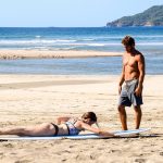 Dreamsea Costa Rica Surf Camp | backpacking, travel, hostel, surf, and yoga camp | Media Files | Lifestyle Image of Surf and Yoga Camp Resort | man teaching a girl how to surf at Dreamsea Surf Camp on a beach in Tamarindo, Costa Rica
