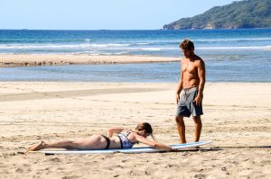 Dreamsea Costa Rica Surf Camp | backpacking, travel, hostel, surf, and yoga camp | Media Files | Lifestyle Image of Surf and Yoga Camp Resort | man teaching a girl how to surf at Dreamsea Surf Camp on a beach in Tamarindo, Costa Rica
