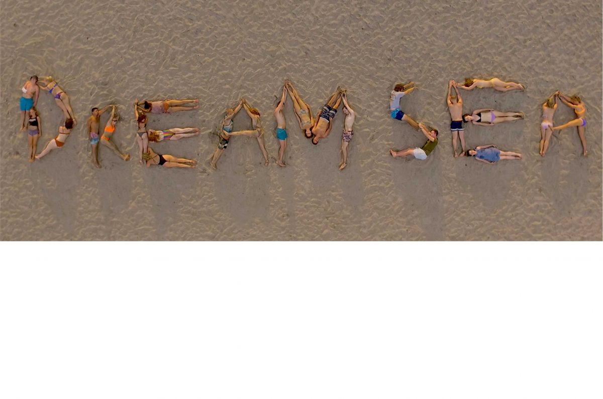 Dreamsea Costa Rica Surf Camp | backpacking, travel, hostel, surf, and yoga camp | Media Files | Lifestyle Image of Surf and Yoga Camp Resort | men and women laying on sand spelling out the words: 'Dreamsea' with their bodies on a beach in Tamarindo, Costa Rica
