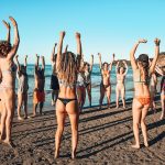 Dreamsea Costa Rica Surf Camp | backpacking, travel, hostel, surf, and yoga camp | Media Files | Lifestyle Image of Surf and Yoga Camp Resort | group of individuals jumping up and cheering in swimsuits on a beach in Tamarindo, Costa Rica at Dreamsea Surf Camp Costa Rica