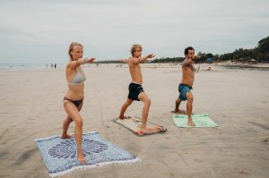 Dreamsea Costa Rica Surf Camp | backpacking, travel, hostel, surf, and yoga camp | Media Files | Lifestyle Image of Surf and Yoga Camp Resort | 3 individuals posing in warrior 1 for Yoga on a beach in Tamarindo, Costa Rica