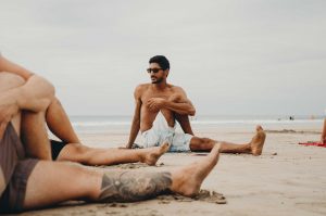 Dreamsea Costa Rica Surf Camp | backpacking, travel, hostel, surf, and yoga camp | Media Files | Lifestyle Image of Surf and Yoga Camp Resort | guy stretching and preparing for Yoga on a beach in Tamarindo, Costa Rica at Dreamsea Surf Camp Costa Rica