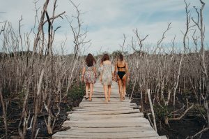 Dreamsea Costa Rica Surf Camp | backpacking, travel, hostel, surf, and yoga camp | Media Files | Lifestyle Image of Surf and Yoga Camp Resort | Dreamsea Costa Rica Surf Camp | backpacking, travel, hostel, surf, and yoga camp | Media Files | Lifestyle Image of Surf and Yoga Camp Resort | Girls walking away from a camera on a pier that goes through a beach tree forest near a beach in Tamarindo, Costa Rica