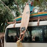Dreamsea Costa Rica Surf Camp | backpacking, travel, hostel, surf, and yoga camp | Media Files | Lifestyle Image of Surf and Yoga Camp Resort | Individuals loading a bus with surfboards on a roof rack in tamarindo costa rica