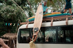Dreamsea Costa Rica Surf Camp | backpacking, travel, hostel, surf, and yoga camp | Media Files | Lifestyle Image of Surf and Yoga Camp Resort | Individuals loading a bus with surfboards on a roof rack in tamarindo costa rica