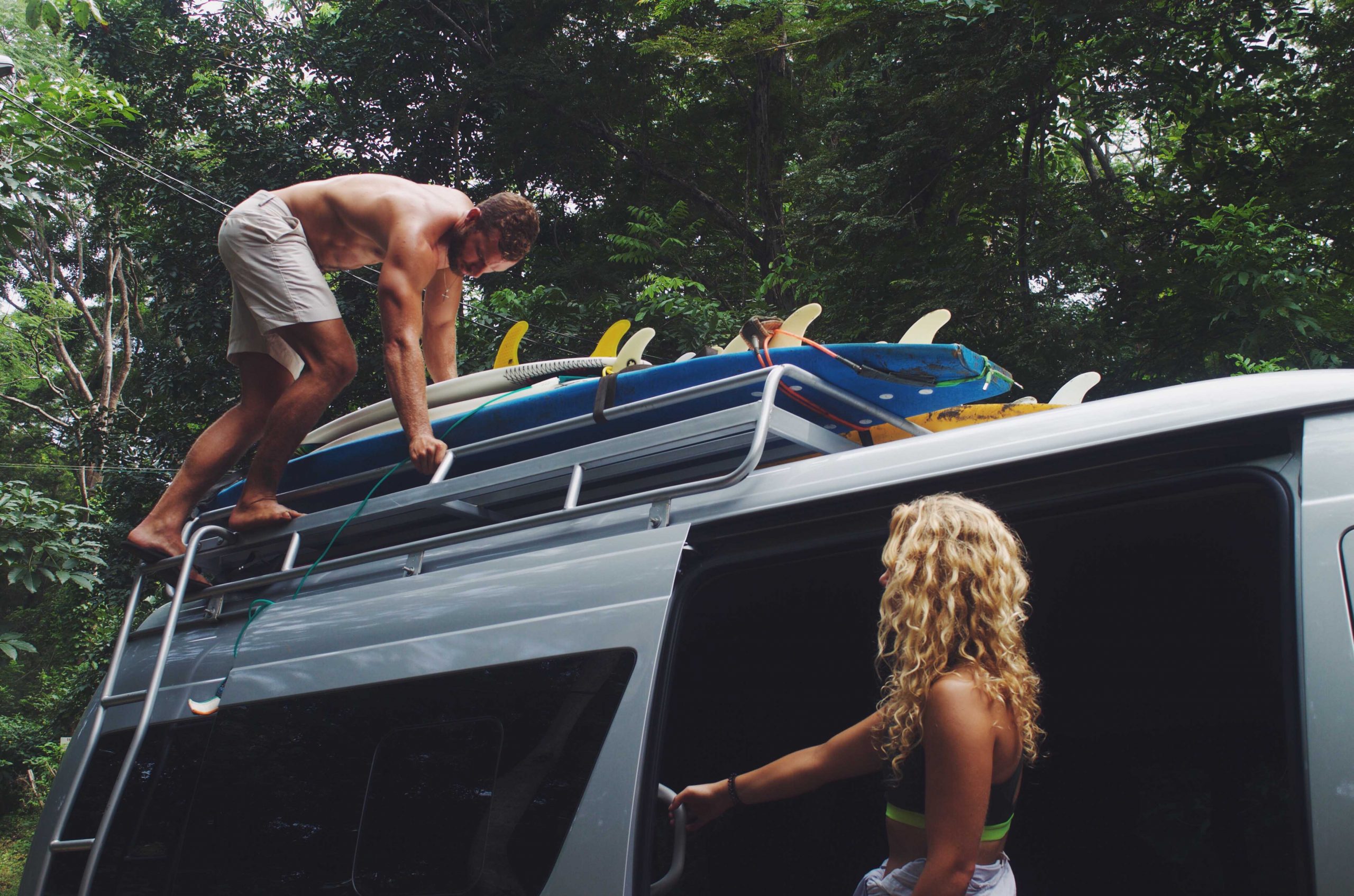 Dreamsea Costa Rica Surf Camp | backpacking, travel, hostel, surf, and yoga camp | Blog | picture of a man putting surfboards on roof of car and a beach girl